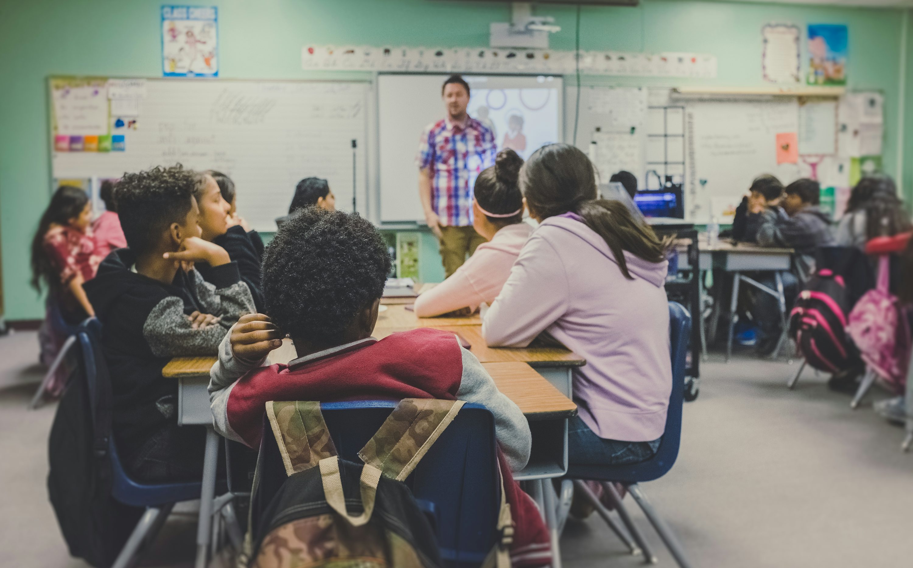 Teacher presenting lesson slides to students in a classroom